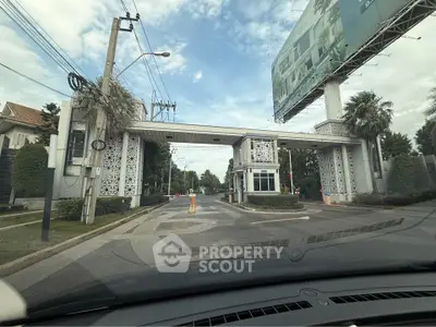 Gated community entrance with security booth and lush greenery