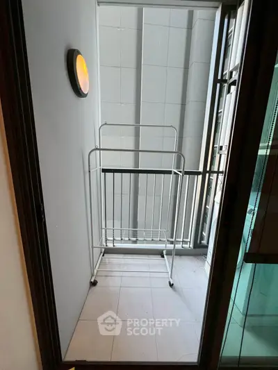 Compact balcony with railing and wall-mounted light, ideal for small outdoor space in urban apartments.