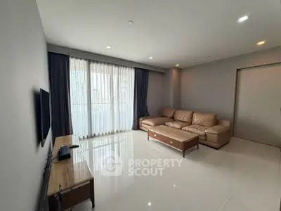 Spacious modern living room with large windows and elegant furnishings.