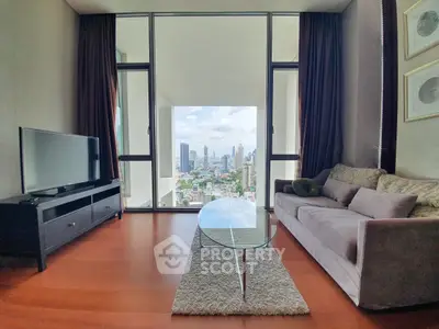 Modern living room with stunning city view through large windows, featuring sleek furniture and wooden flooring.