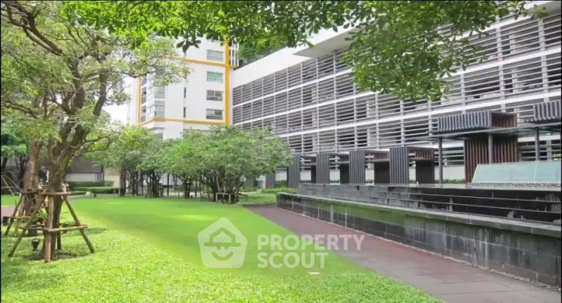 Modern building with lush green garden and sleek architectural design, perfect for urban living.