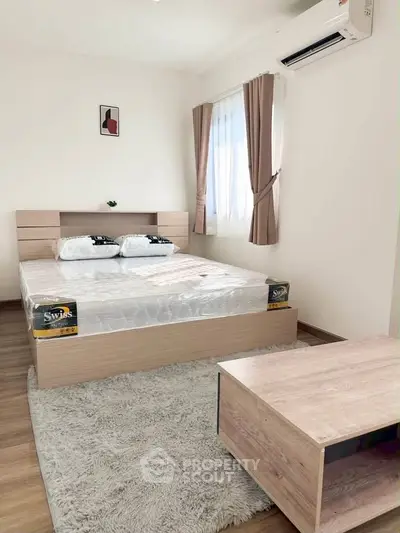 Cozy bedroom with modern decor, featuring a comfortable bed and natural light from large windows.