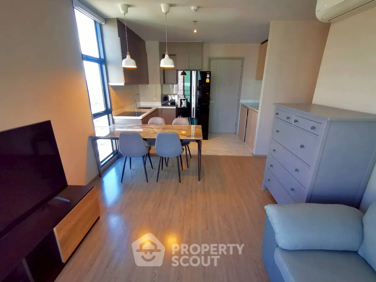 Modern open-plan living room with dining area and kitchen in stylish apartment.