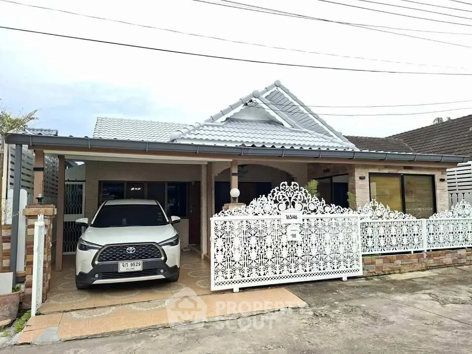 Charming single-story house with decorative white fence and carport in a suburban neighborhood.