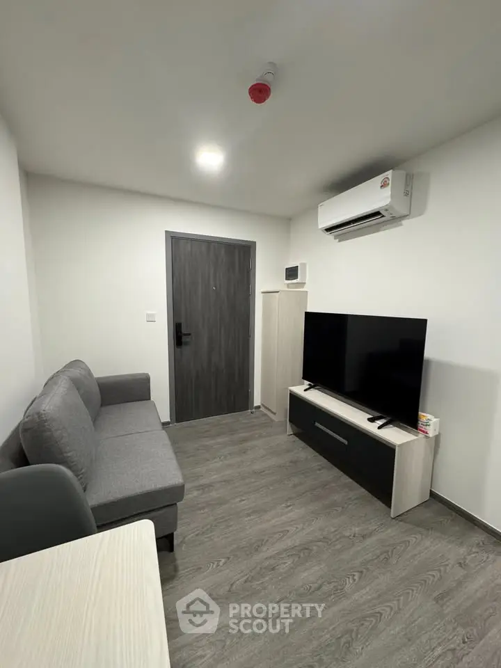 Modern living room with sleek furniture and air conditioning in a compact apartment.