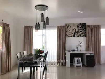 Spacious dining area with modern decor and natural light, featuring elegant pendant lighting and a stylish desk.