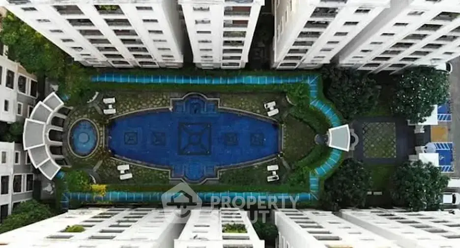 Stunning aerial view of luxurious residential complex with central pool and lush greenery.