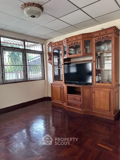 Spacious living room with elegant wooden cabinet and large windows offering natural light.