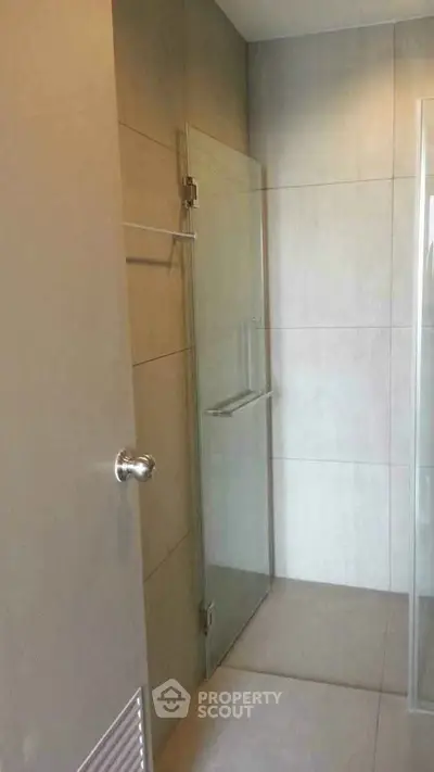 Modern minimalist bathroom with glass shower enclosure and sleek tile design.