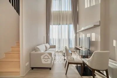 Modern living room with high ceilings and large windows, featuring elegant furniture and natural light.