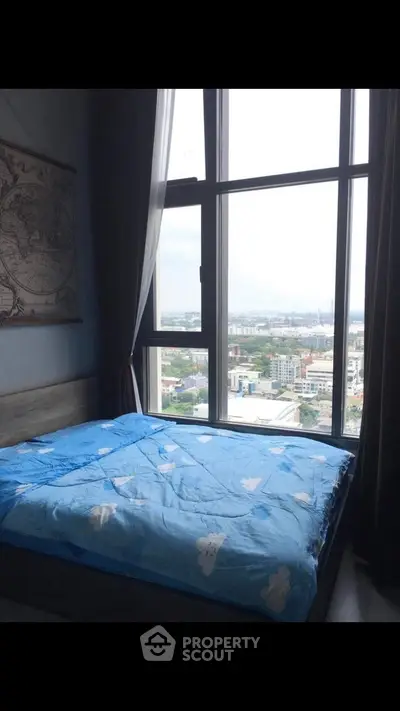 Cozy bedroom with large window offering stunning city view, perfect for relaxation and comfort.