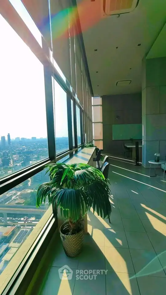 Stunning high-rise building view with floor-to-ceiling windows and lush indoor plant.