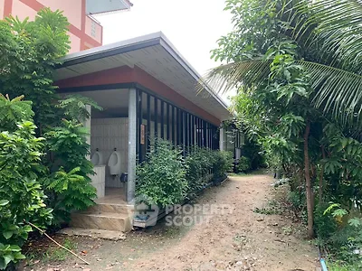 Charming garden pathway leading to a modern building with lush greenery.