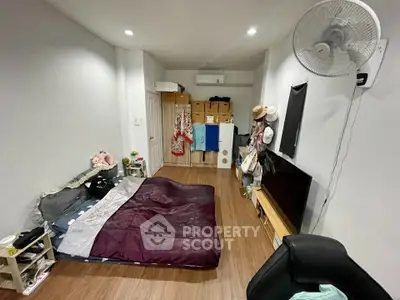 Cozy bedroom with modern decor and wooden flooring, featuring a wall-mounted fan and ample storage space.