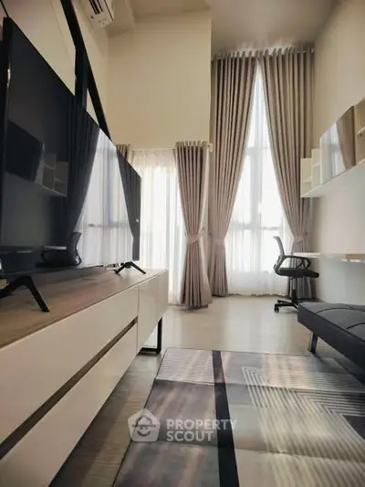 Modern living room with high ceilings and large windows, featuring stylish furniture and natural light.