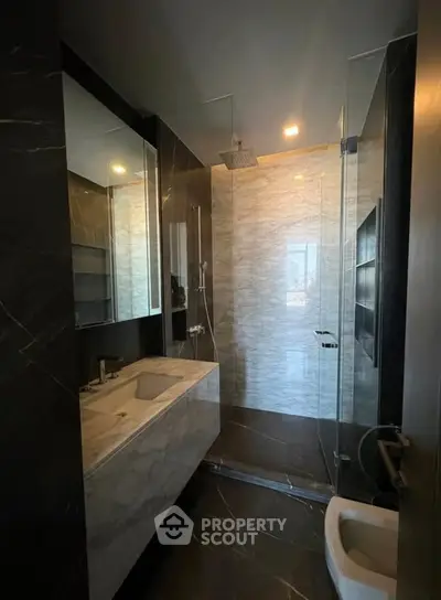 Luxurious modern bathroom with sleek marble finishes and glass shower enclosure.