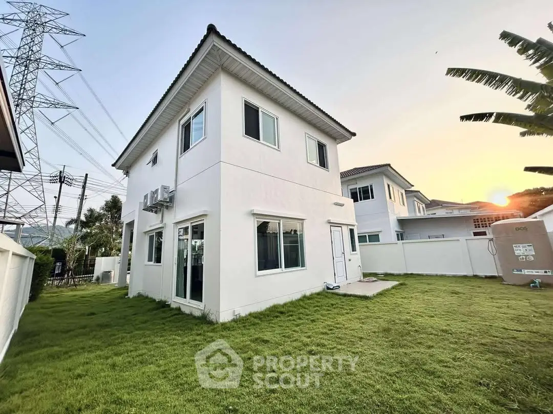 Charming two-story home with lush green lawn and sunset view