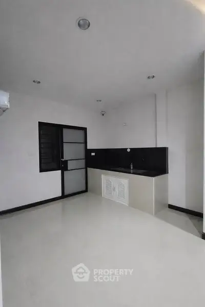 Modern minimalist kitchen with sleek black countertops and ample storage space.