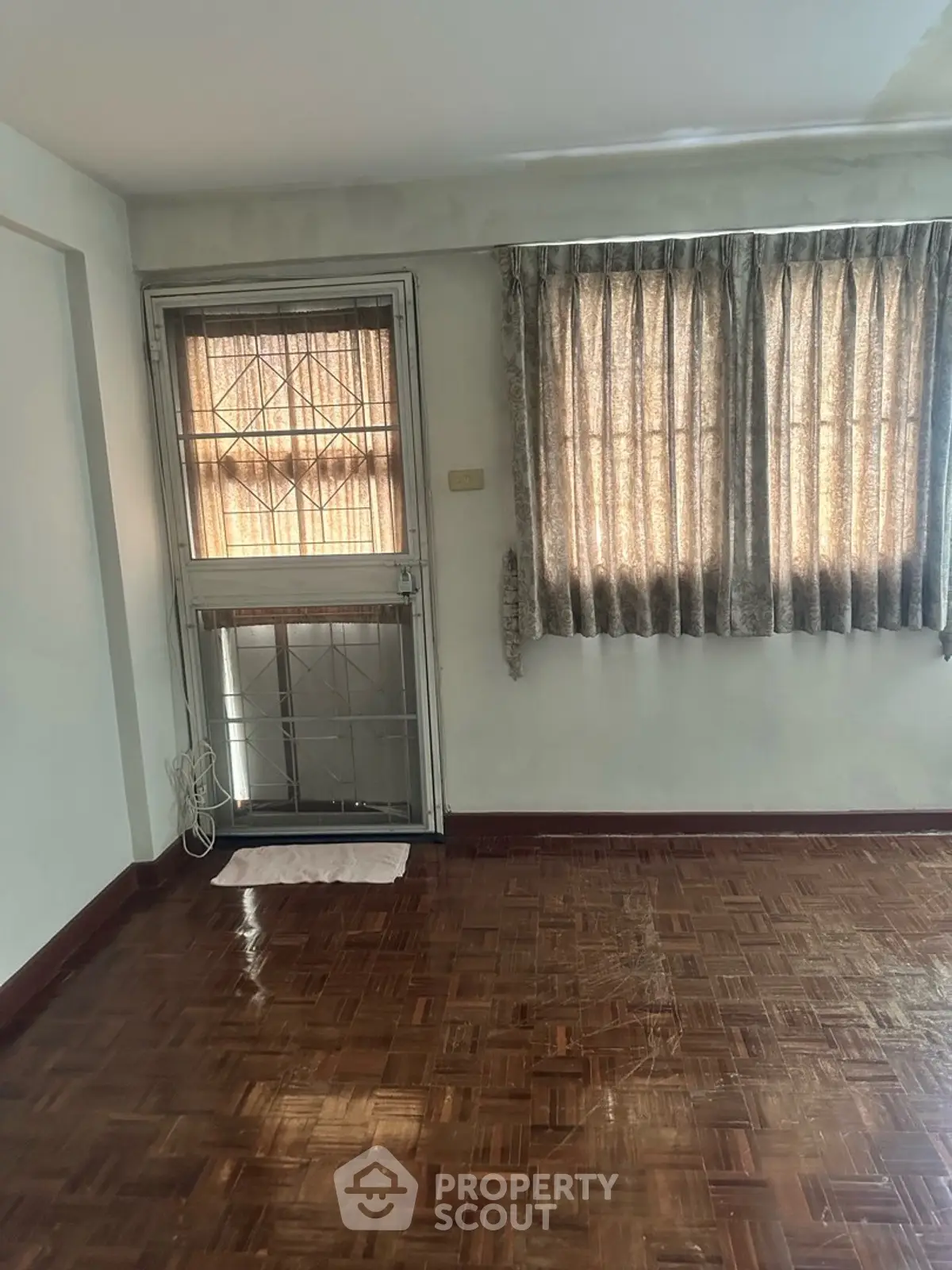 Spacious room with parquet flooring and large window, perfect for natural light.