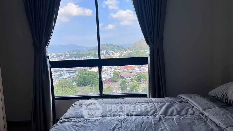 Cozy bedroom with stunning city view through large window and elegant curtains.