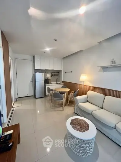 Modern living room with cozy seating and dining area, featuring sleek kitchen appliances.