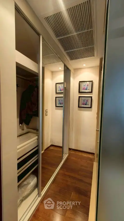 Elegant walk-in closet with mirrored sliding doors and wooden flooring