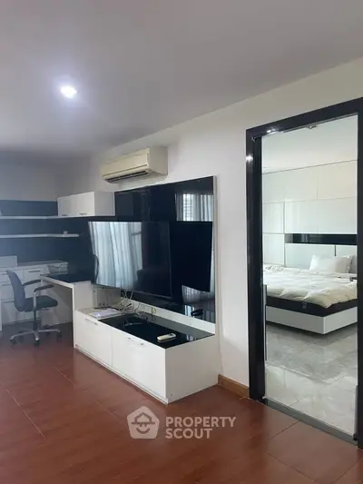 Modern living room with sleek furniture and a glimpse into a cozy bedroom, perfect for urban living.