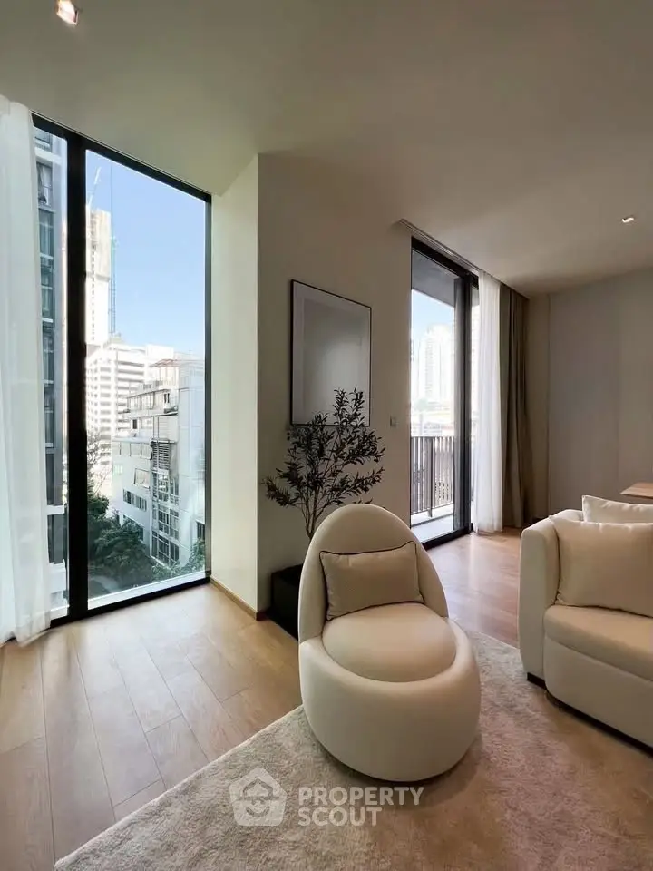 Modern living room with floor-to-ceiling windows and city view, featuring elegant furniture and natural light.