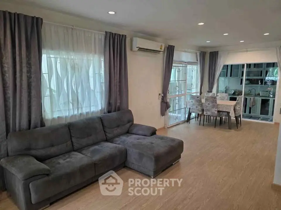 Spacious living room with modern decor and open layout leading to dining area and kitchen.