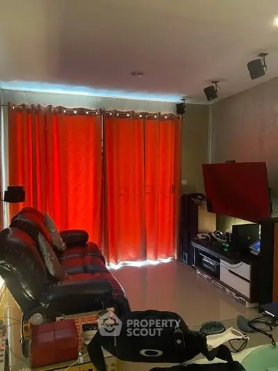 Cozy living room with red curtains and leather sofa, perfect for relaxation and entertainment.
