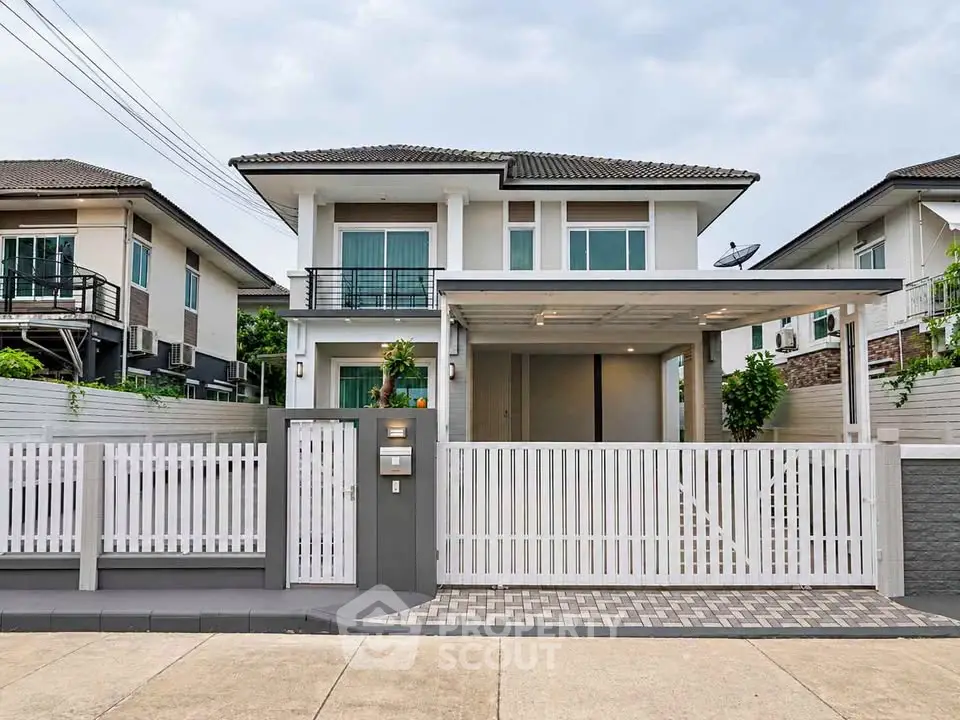 Modern two-story house with gated entrance and driveway in a suburban neighborhood.