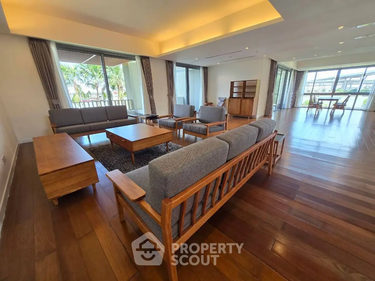 Spacious living room with elegant wooden furniture and large windows offering a scenic view.