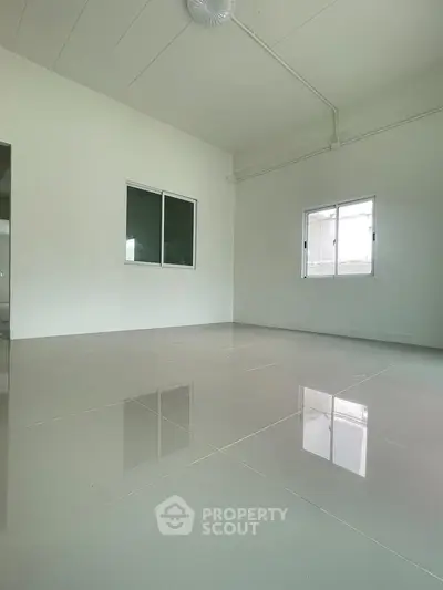 Spacious empty room with glossy tiled flooring and large windows, perfect for customization.