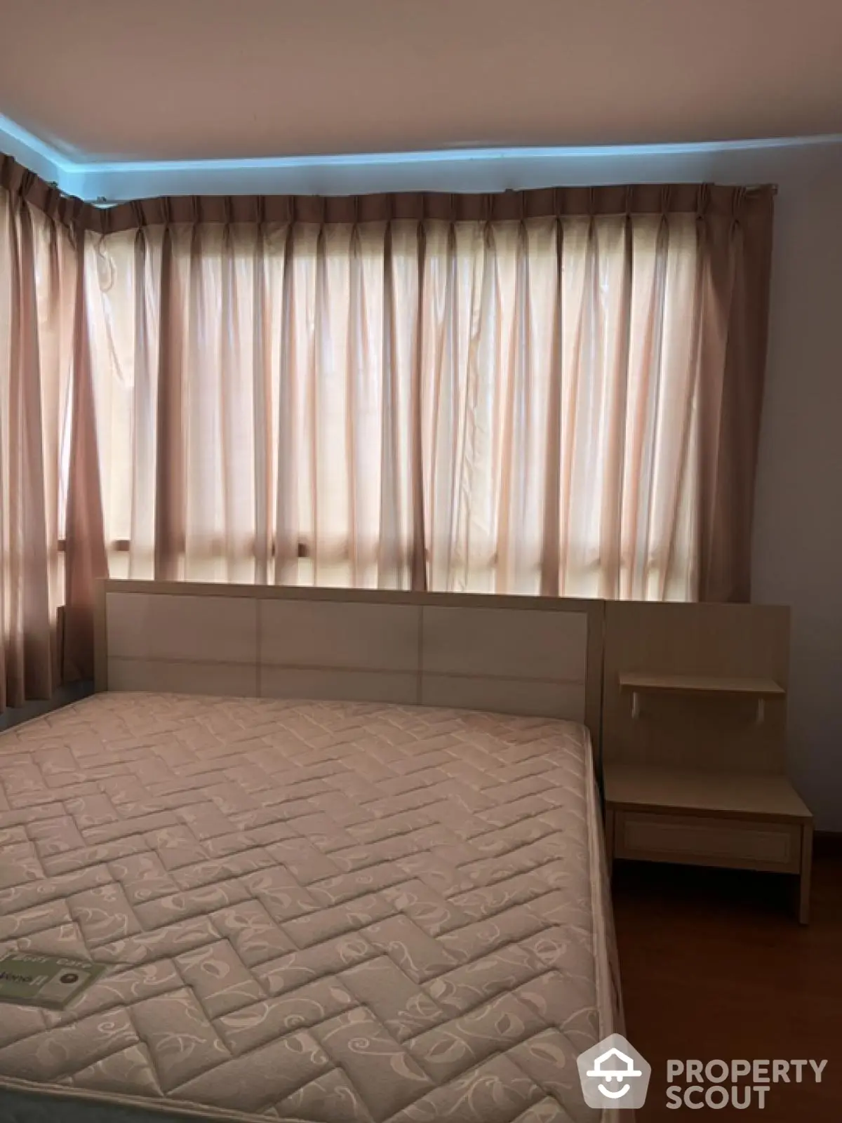 Cozy bedroom with large windows and natural light, featuring a comfortable bed and elegant curtains.