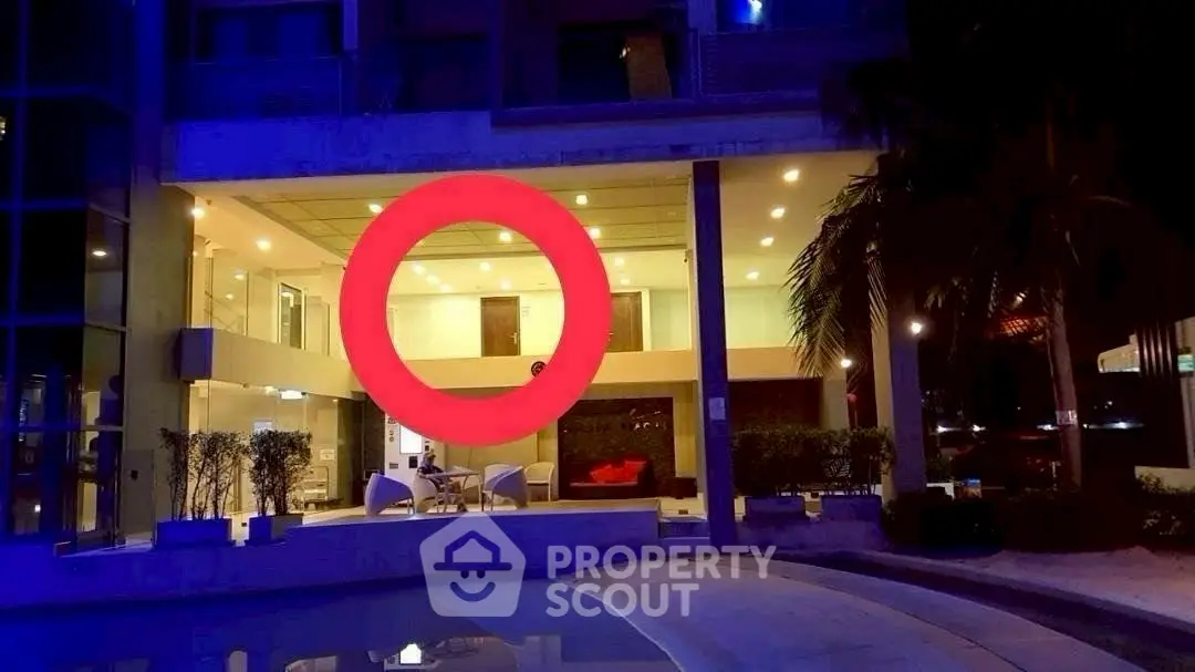 Modern luxury building exterior with illuminated poolside and stylish seating area.