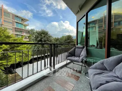 Charming balcony with cozy seating and scenic view in modern apartment complex.