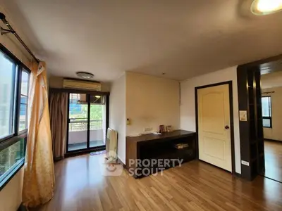 Spacious living room with wooden flooring and balcony access in modern apartment