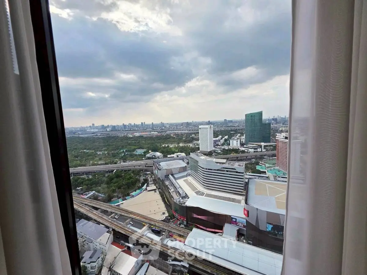 Stunning cityscape view from high-rise window showcasing urban skyline and lush greenery.