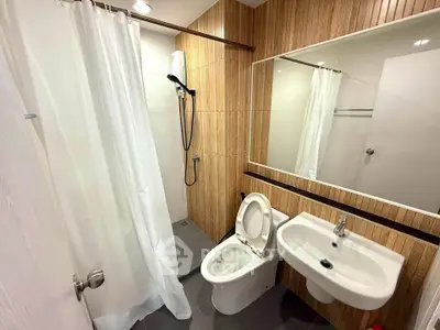Modern bathroom with wood paneling, shower, and white fixtures in a stylish apartment.