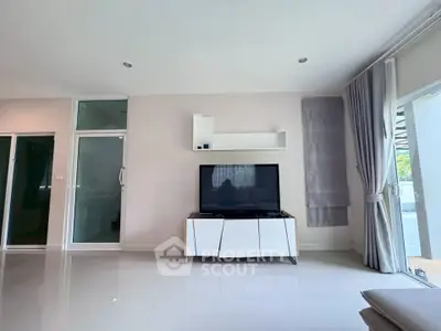 Modern living room with sleek TV stand and large windows offering natural light.