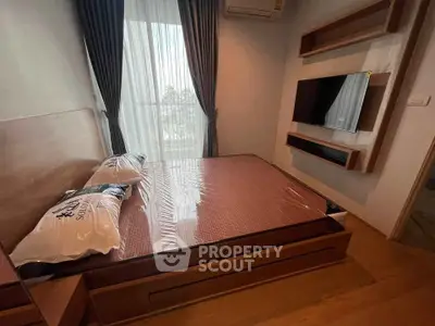 Modern bedroom with sleek design and natural light, featuring a wall-mounted TV and stylish decor.