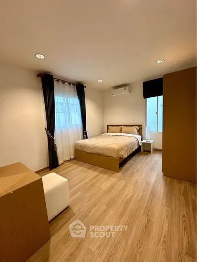 Spacious bedroom with modern furnishings and natural light, perfect for relaxation.