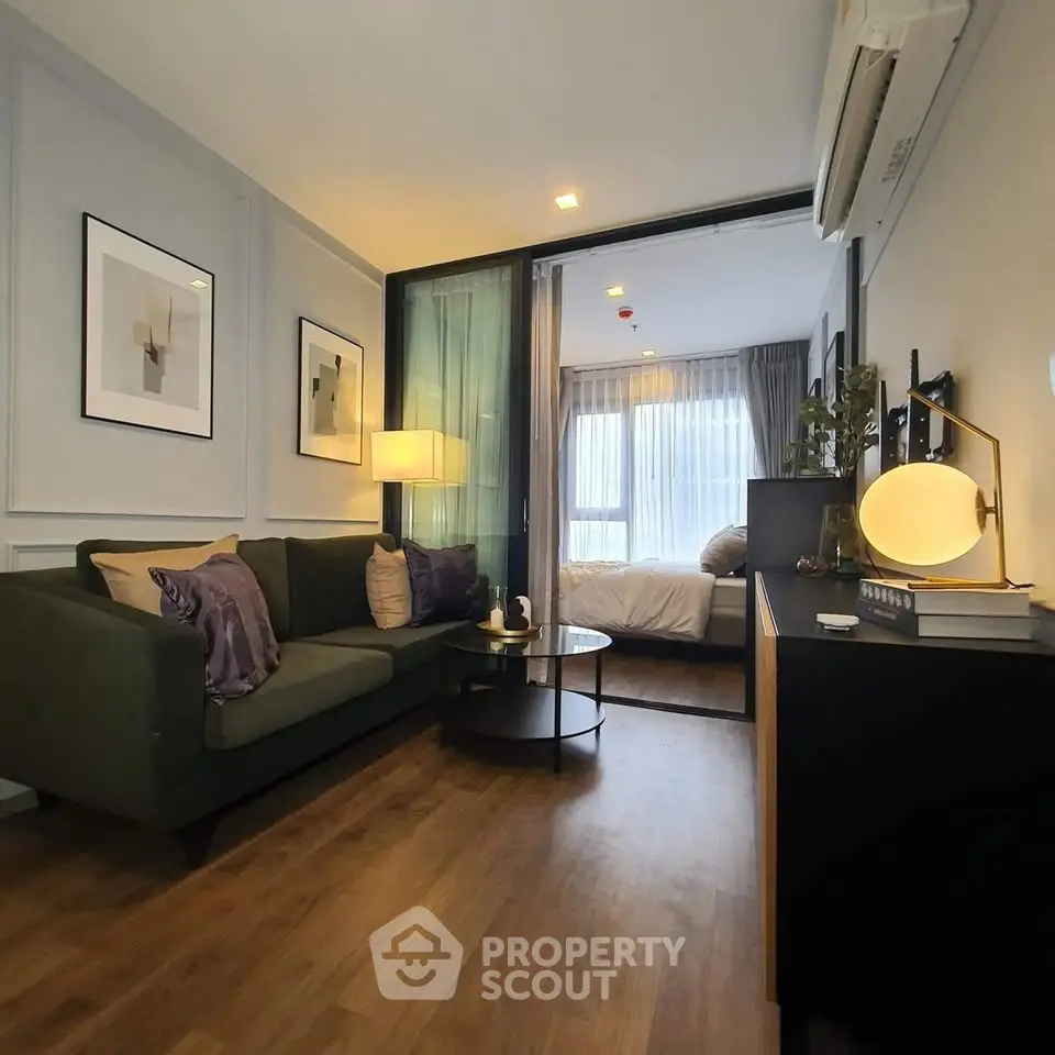 Modern living room with cozy sofa and stylish decor leading to a bright bedroom.