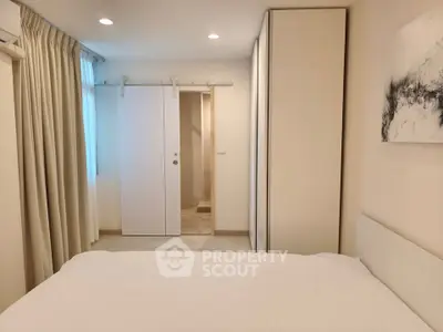 Modern bedroom with sliding door and minimalist decor in a cozy apartment.