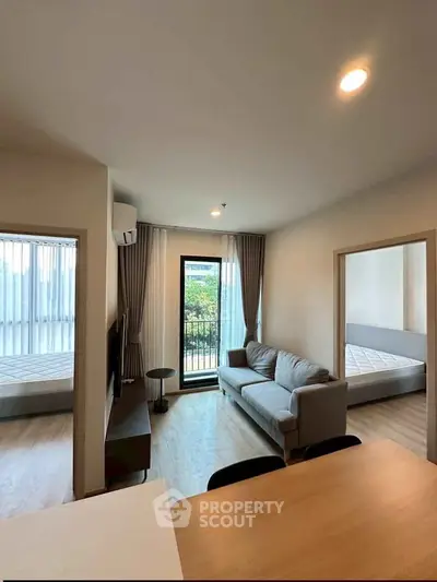 Modern apartment interior with cozy living room and natural light, featuring a sofa and balcony access.