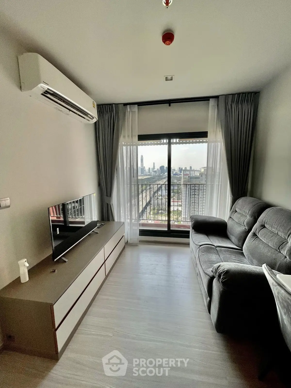 Modern living room with city view, featuring sleek furniture and large windows for natural light.