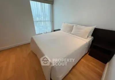 Cozy bedroom with large window and wooden flooring in modern apartment.