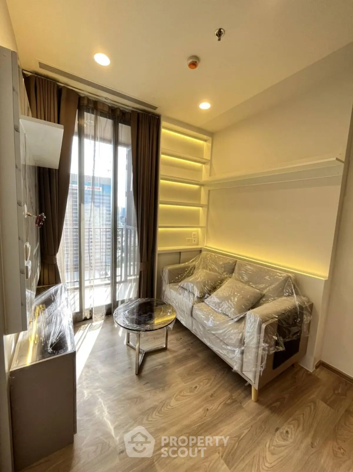 Modern living room with floor-to-ceiling windows and stylish furniture in a high-rise apartment.
