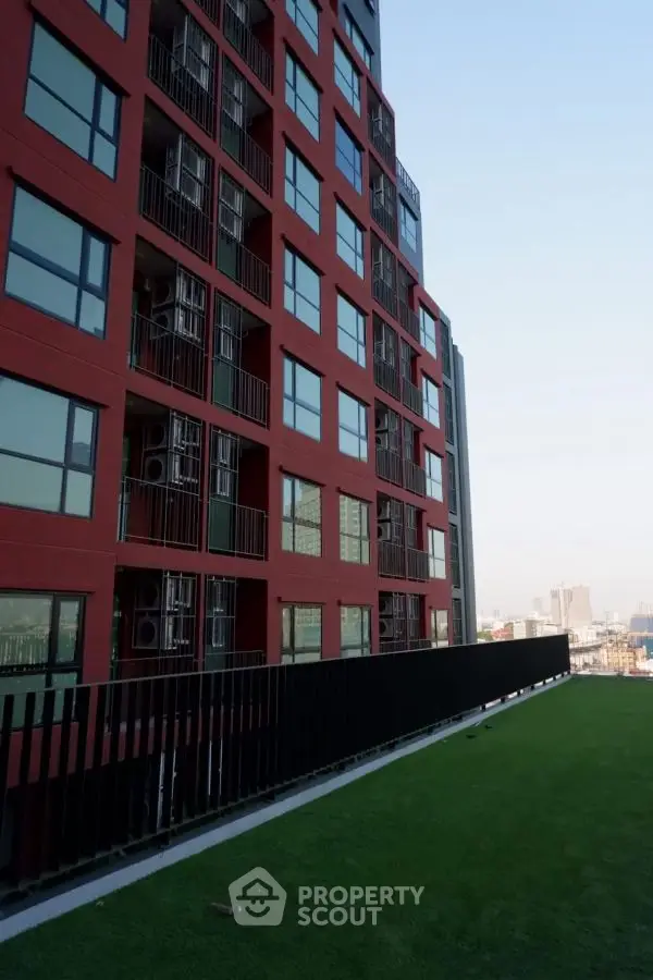 Modern red building with city view and green rooftop terrace
