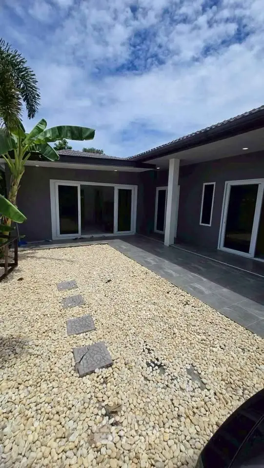 Modern single-story home with sleek exterior and stone pathway under a clear blue sky.